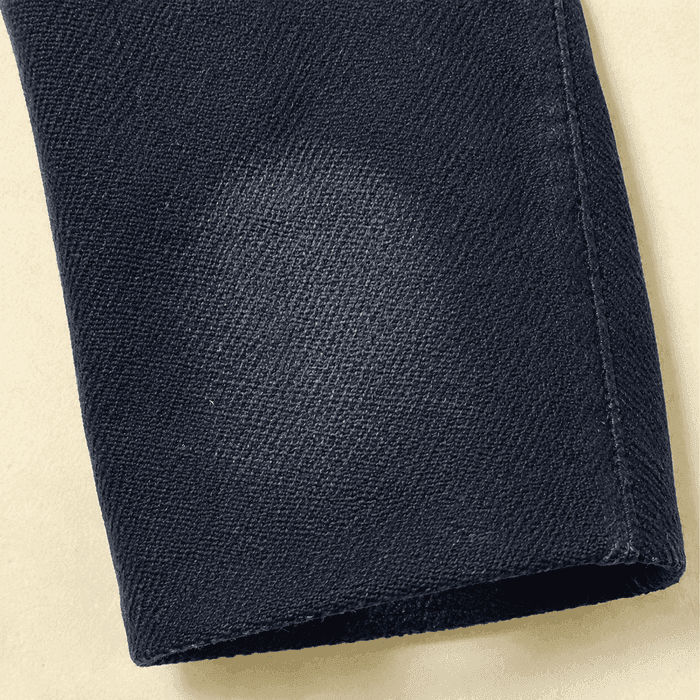 The rubbed, faintly shiny elbow of a navy wool blazer sleeve.