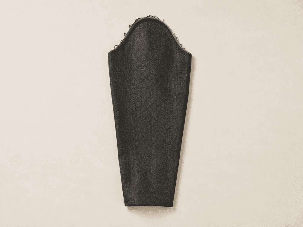 A single detached wool coat sleeve laid flat and alone on a large paper backdrop.